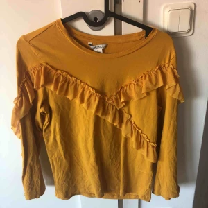  - Gul tröja från Monki storlek S med volanger, säljes då den inte kommer till användning. Köparen står för eventuell fraktkostnad. 