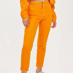 Topshop jeans - Orangea mom- jeans från topshop som är använda ett fåtal gånger! Sitter skitsnyggt men de är lite stora på mig! 26 i midja men skulle passa 27 också. 30 i längd!