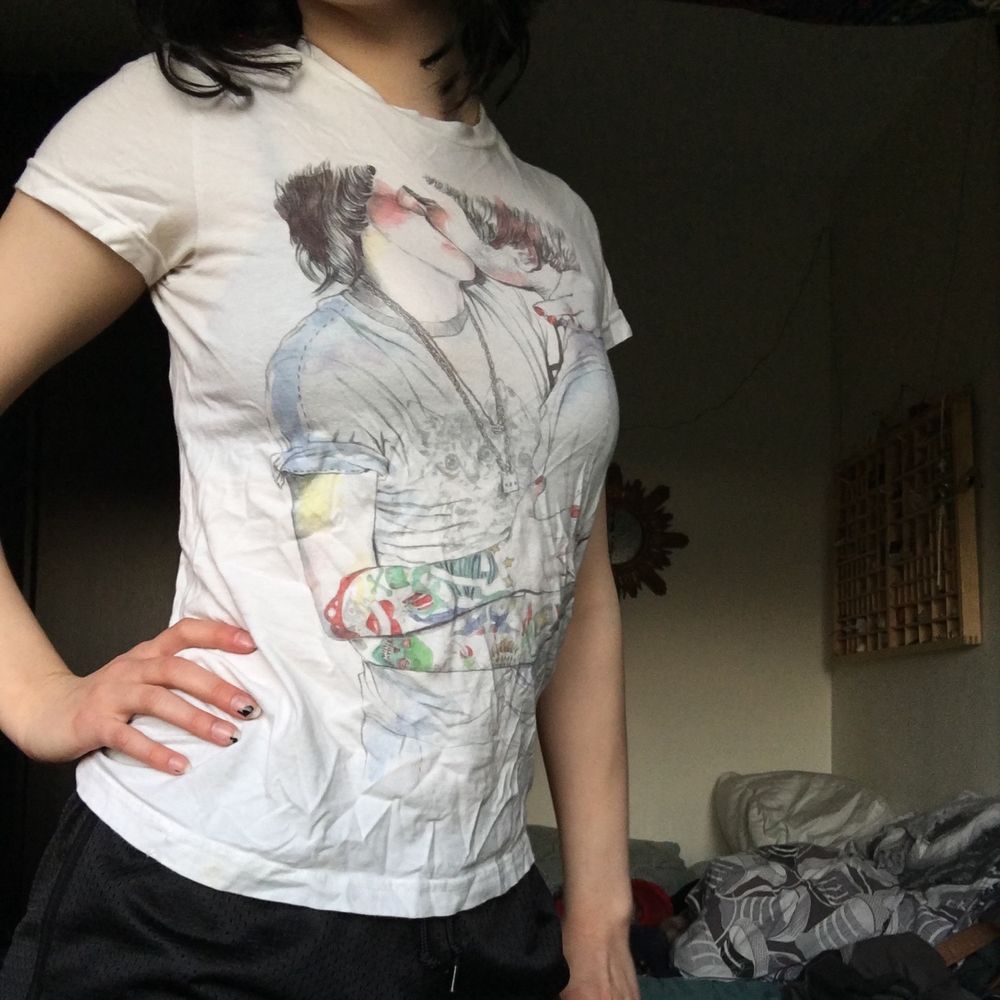 En skön secondhand vit T-shirt från T-POST med design som förseställer två personer som kysser varandra, om man vänder ut och in på t-shirten så står det lite om inspirationen till designen och om designern Esra Røise. Uppskattad storlek är S, Frakt 22 kr. T-shirts.