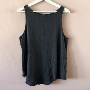 Träningstopp från Under Armour - Mörkgrå träningstopp från Under Armour i Stretchigt mobilsurf. Öppen slits i ryggen. 