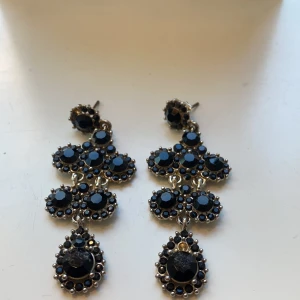 Svarta örhängen - Ett par fina Lily and rose örhängen i svart! Väl använda & två stycken svarat stenar saknas, samt limmat på en svart Sten i mitten längre upp på de vänstra örhänget men syns ej tydligt.