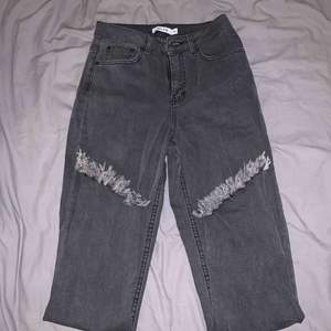 Gråa jeans från NA-KD med slitningar nedtill, aldrig använda då de är för små, köparen står för frakt 