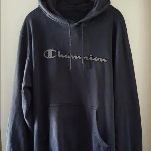  - Vintage mörkgrå Champion hoodie. Storlek XL men tycker den sitter snyggt oversize på mindre storlekar. I fint skick, ena plastpluppen saknas dock på ena snöret som kan ses på bild 2. Fraktkostnad blir 79kr.