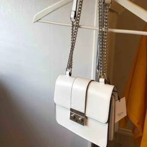  - Oanvänd vit handväska som kan alterneras mellan att hållas i handen och ha cross body eller på axeln. Perfekt t.ex till bröllopet. Inköpt 2018. Mått: 16x20x8cm