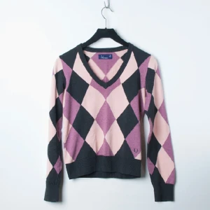  - Jättefin Fred Perry finstickad tröja med rutmönster. Är i lila, rosa, svart färg. Tröjan är inköpt för ett år sedan och har använts sparsamt. Mycket fint skick och har inga skav eller slitningar. Storlek 36.