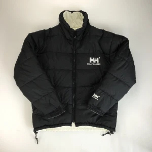 Helly Hansen Reversible Puffer jacket - Säljer min tjocka vinterjacka. Köpt på secondhand så det finns täcken på användning, några små hål samt att snörena är lite konstiga på vissa ställen (om intresse finns skickar jag givetvis bilder!) Går att ha på båda hållen. (Obs inte mina bilder,tagna från Depop @olesstore, men är exat samma jacka) Ganska stor men hade den som oversized:)