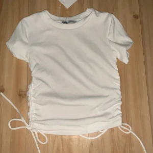 Vit t-shirt - Vit-shirt med knytning på sidan, jätte fin och gullig från Zara och aldrig andvänd för den är förliten för mig tyvärr:( 