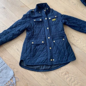 Barbour jacka -  Mörk blå barbour jacka i fint skick! Insidan av den ena fickan är lite sönder men inget som märks eller syns! Storlek barn XL vilket  betyder 152/158! Säljer pga för liten! Luvan är av och påbar