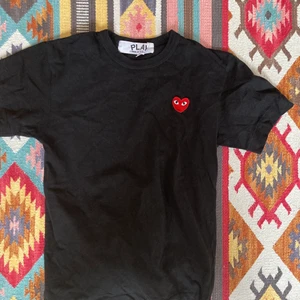 En Comme Des Garcons Play tshirt  - Super fin CDG play tröja i bra skick! Enbart använd ett fåtal gånger, säljs pga att jag har samma tröja i anan färg! Nypris: 1200kr