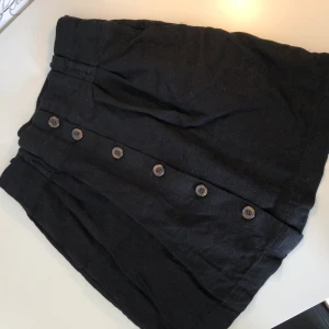 Kjol - Oanvänd svart kjol med knappar.