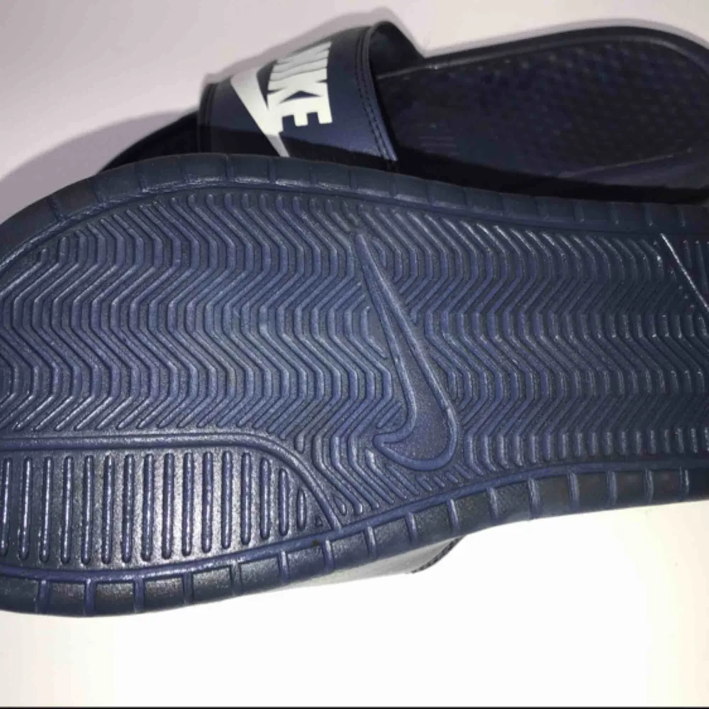 Ett par marinblå Nike tofflor. Har använts som inneskor, därför inte så slitna. Säljs för 150kr. Betalning sker via swisch :)) köparen står för frakt. Övrigt.