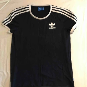  - Adidas tröja i mörkblått, backsidan är i ett siden material. Tröjan är använd ett fåtal gånger och i gott skick. Storleken är XS men är oversized model