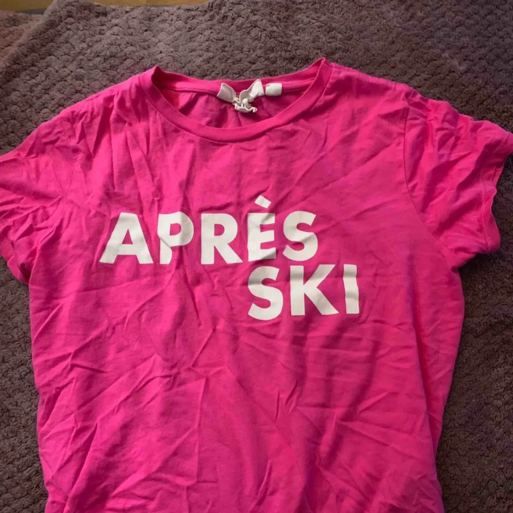 Cerise/skrikrosa T-shirt med texten ”Après ski”. Storlek XS från H&M. Endast använd hemma en gång eftersom jag har minst 50 andra t-shirts. Väldigt bra skick 💕. T-shirts.