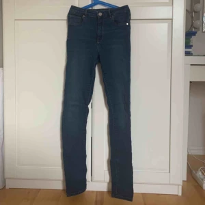  - Ett par mörkblåa, stretchiga, tajta jeans.