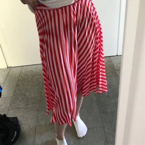 Randig kjol från Gina Tricot - Randig kjol i röd och rosa från Gina Tricot. Modellen är lite längre och slutar ungefär mitt på varden på mig. Aldrig använd så i mycket bra skick! 