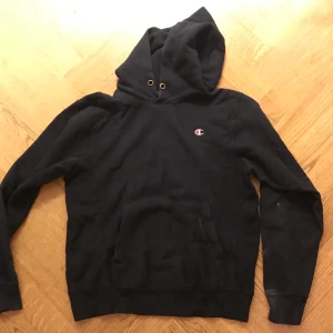 Mörkblå champion hoodie - Mörkblå champion hoodie köpt på secondhand i Frankrike. Lite bleknade fläckar på slutet av armarna men annars i fint skick.