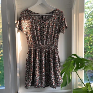 Blommig klänning - Supersöt blommig klänning från HM!! Storlek 38. Har knappar på övderdeln, en resår i midjan och bäst av allt - fickor!! Ärligt talat en av dom bekvämaste klänningarna jag har testat. 