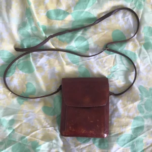 Liten väska - En gammal favorit! En liten väska som är extremt rymlig för sin storlek. Jag brukar få med allt jag ska ha på typ en utekväll i den. Tre stora och två små fack. Väskan är 18 x 15 cm. Axelbandet är justerbart: minst 63 cm, längst 145 cm (rätt långt).