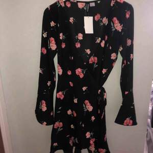 Svart omlottklänning med blommor från H&M i storlek 36. Aldrig använd så nyskick. Frakt tillkommer