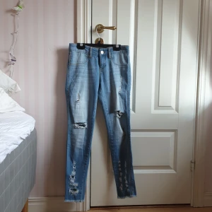 Jeans med slitning - Blåa jeans med slitningar på båda benen. Igensydda fickor fram och fransar längst ner på byxan. Hör av dig vid intresse eller vill ha fler bilder😊💕