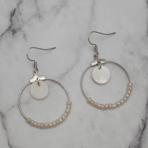  - Fina silverfärgade örhängen med pärlor av äkta snäckskal. 