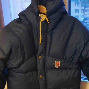  - Fjällräven vinterjacka i mörkblå. Strl XXXS. Pyttelitet hål i ärmen  som är lagat. 