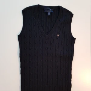  - Preppy kabelstickad slipover väst i marinblå från Gant. Västen är i mycket fint skick, använd endast 2 ggr. Köptes för ca 1000 kr 