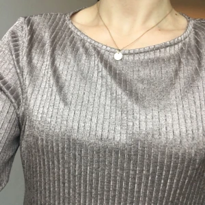  - Guldskimrande trikåtopp från HM. Rätt löst sittande i stl S och stretchigt material så passar XS-M beroende på önskad passform. I mkt fint skick! Frakt tillkommer.