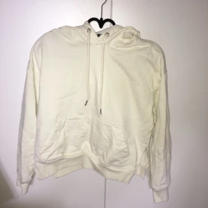  - En vit hoodie från H&M som inte kommer till användning. Den har en ficka på framsidan och öppningar vid sidorna.