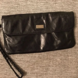  - Liten väska i skinn från kvalitetsmärket Adax. Nypris > 1000kr. Tre "större" fack inuti, varav ett har dragkedja. Så många som 20 kortfack. En lång axelrem saknas men har du en extra så finns det hylsor att sätta fast den i.