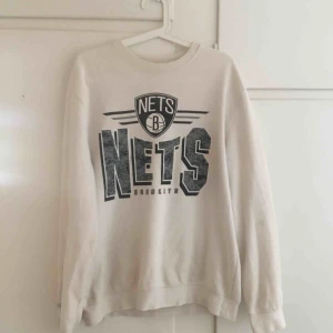  - Snygg collegetröja från Mitchell & Ness i vitt med tryck NETS. 