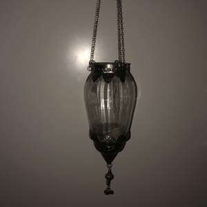 En hängande ljuslykta för värmeljus i silver och glas.