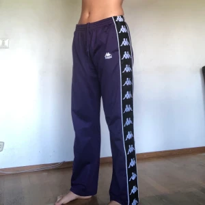 Kappa trackpants, XL - Lila trackpants från Kappa, strl XL , men har vanligtvis M på liknande byxor så passformen skulle beskrivas mer som M/L. Knappt använda så i gott skick! Nypris 500kr. Köparen står för frakt!💖