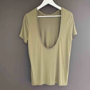  - FRAKT INGÅR! Helt oanvänd t-shirt med v-ringad öppen rygg. Skönt material och fin färg, säljer då jag inte lyckats använda den alls..