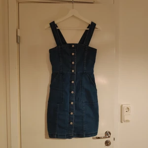 Jeansklänning size 36 - En jeansklänning med knappar på framsidan och fickor. 