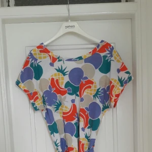  - Härlig klänning i fantastiskt fruktmönstrat tyg! Fin ringning i ryggen med korslagda band. Perfekt vårklänning. Säljes i fint skick!