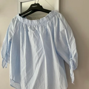 Vitblårandig off-shoulder topp från HM - Vit-blå-randig off-shoulder topp från HM som aldrig är använd 💙🤍 frakt tillkommer och vid flera köpare blir det budgivning som avslutas 24 timmar efter första budet 💙🤍