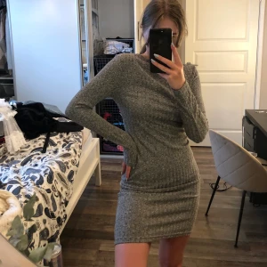 Grå ribbad klänning - En ribbad klänning från hm. Tajt passform men inte obekväm. Storlek 38. Frakt tillkommer