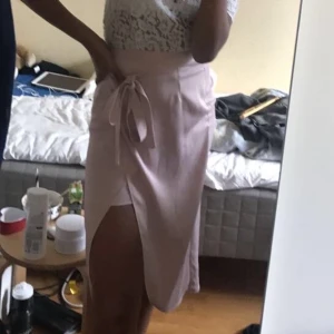 Kjol med slits och knytning  - Gammelrosa kjol från river island med slits och knytning i midjan.  Tyvärr är den för liten för mig . Använd ca 5 gånger.   Storlek: 10, ungefär S eller liten M Inköpspris: 649 kr 