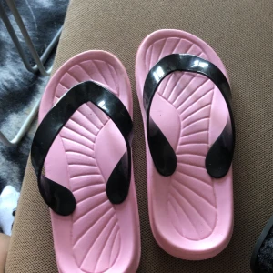 Rosa flipflops  - Rosa med svart ”band” . Bandet är i gummi 