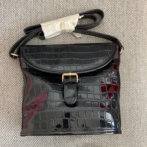 Svart 90-tals väska ⚡️ - OANVÄND, retro väska från 90-talet 🔥 Helt svart med fint ”print” av krokodilskinn (?) såklart EJ äkta skinn 🌟 Dekorativt spänne, den stängs alltså med magnet (se bild 2) ✨ Har ett litet fack med dragkedja 🤩  Köparen står för frakt, hör av er vid frågor 😊