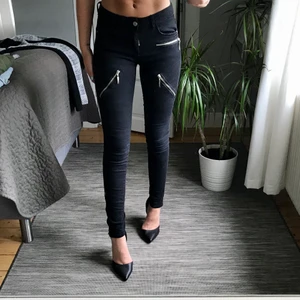 Svarta jeans med zippers - Svarta jeans från Gina Tricot, storlek 34. Jeansen har coola dragkedjor i silver på låren, vid ena framfickan och längst ner på benet. Priset är exklusive frakt, 63kr. 