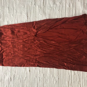 Kjol i siden - Sjukt snygg kjol i siden i 90-tals stuk. Har en mörk roströd färg och en slits i sidan. Använd 2ggr och den förtjänar mer då den köptes för 600kr