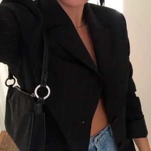 Axelremsväska  - Svinsnygg 90tals axelremsväska. Den är svart med rostsilver detaljer. Ser väldigt retro ut. Köpt på mango för ca 1 år sedan. Passar till allt! 150kr eller högst bud. 💫