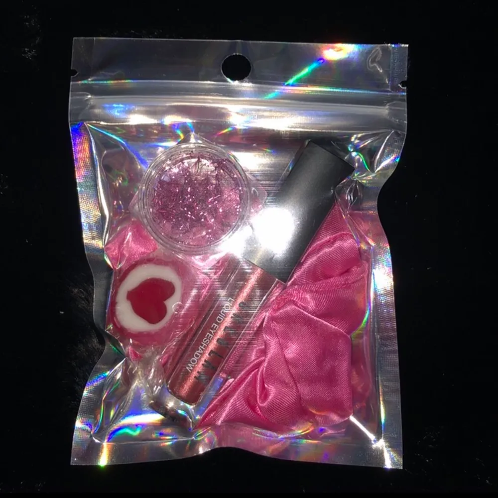 Rosa tema goodiebag som innehåller en velvet scrunchi, liquid eyeshadow, nagel glitter och lite godis❤️ helt oanvänt smink. 49kr plus 11kr frakt💖. Accessoarer.