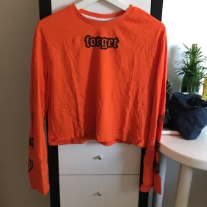 Orange långärmad kortare tröja - Snygg långärmad tröja i en lite kortare modell. ”Forget” på framsidan och lite tryck vid ärmsluten, fråga för fler bilder. Storlek 34/36/xs/s (lappar avklippta). Frakt tillkommer💕