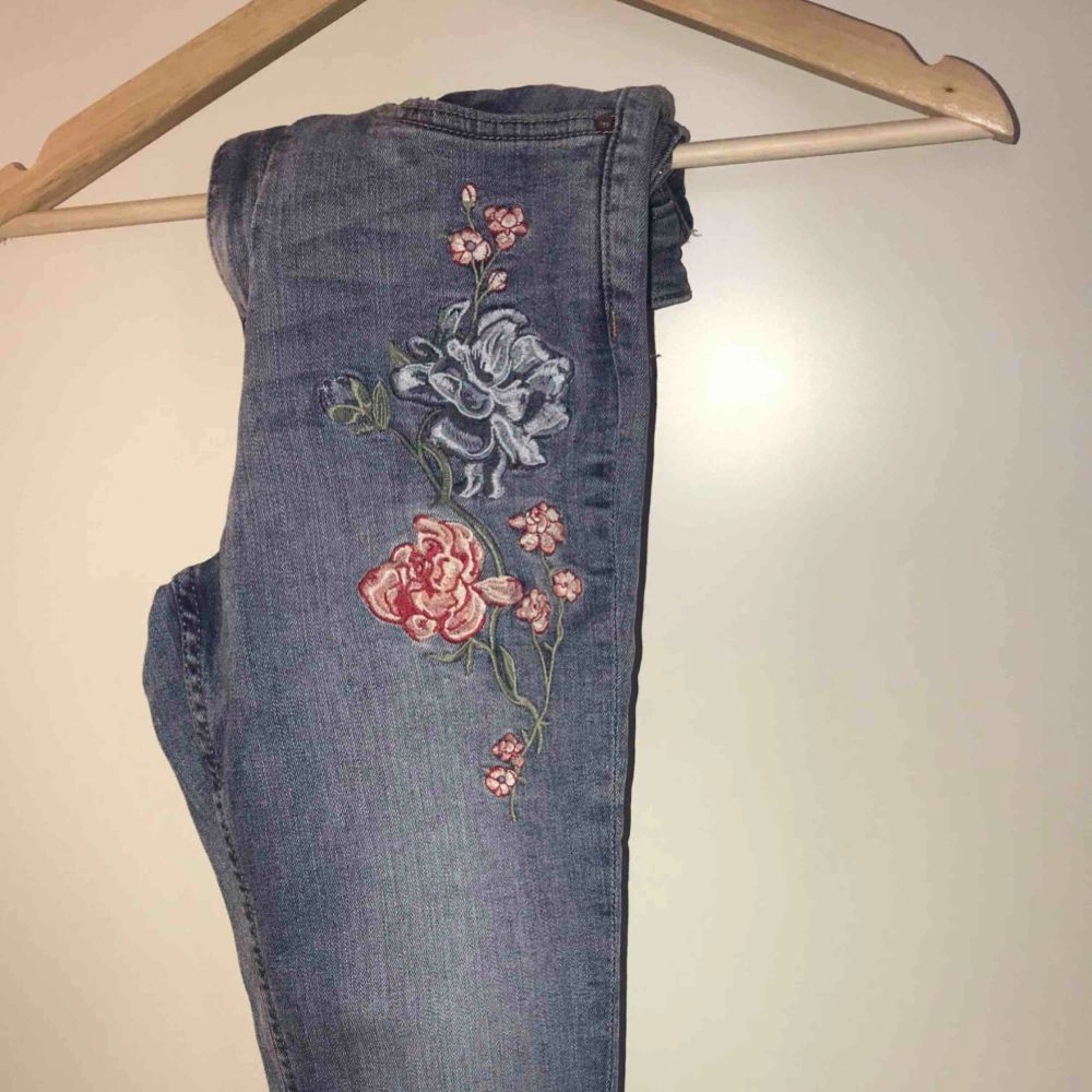 Jag säljer ett par jeans från H&M, dom har blommor broderat på vänster ben. Stl: 34 Dom kommer från ett djur och rökfritt hem.. Jeans & Byxor.