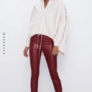 Röda skinnbyxor med slits - Ett par röda skinnbyxor med slits i fram som går att justera med en dragkedja. De stängs även på sidan med en dragkedja. Bra skick. Köparen står för frakten ✨