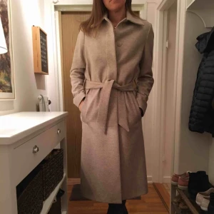  - Superfin beige kappa ”Iza Long Wool Coat” från Filippa K. Inköpt på Design Only.  Prisetikett inkl extra knapp finns. Ordinarie pris 4099 kr, använd endast ett fåtal gånger. Vid intresse finns fler bilder på Naked’s hemsida där den säljs just nu.