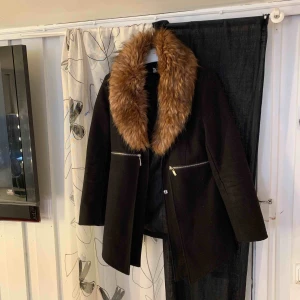 Höstkappa  - Kappa med fuskpälskrage från DM i väldigt bra skick. Enda defekten är att lappen där storleken står har lossnat på ena sidan. Köpte den för 999kr. Frakt tillkommer. 